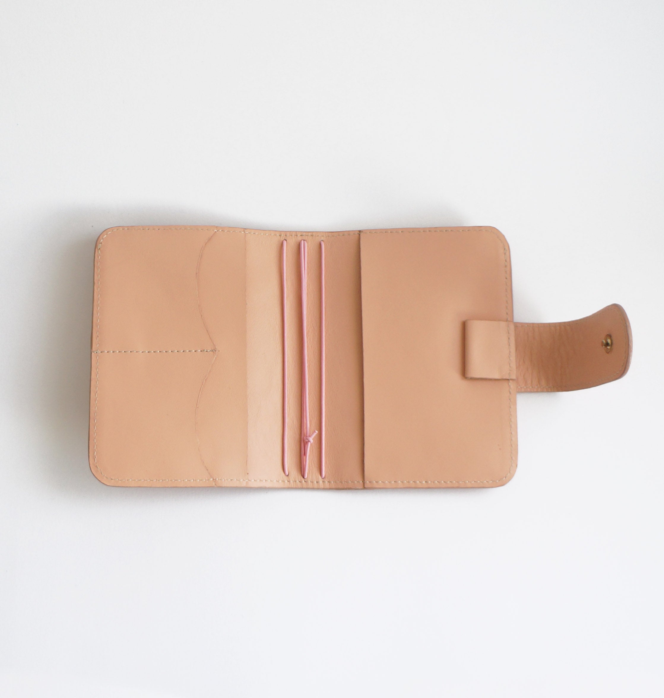 Open view of Passport TN cover in blush leather – shows interior pockets, pink elastic strings and snap closure strap